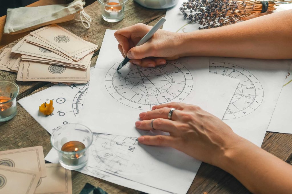 Kobieta tworząca wykres astrologiczny z kart tarota i świecami